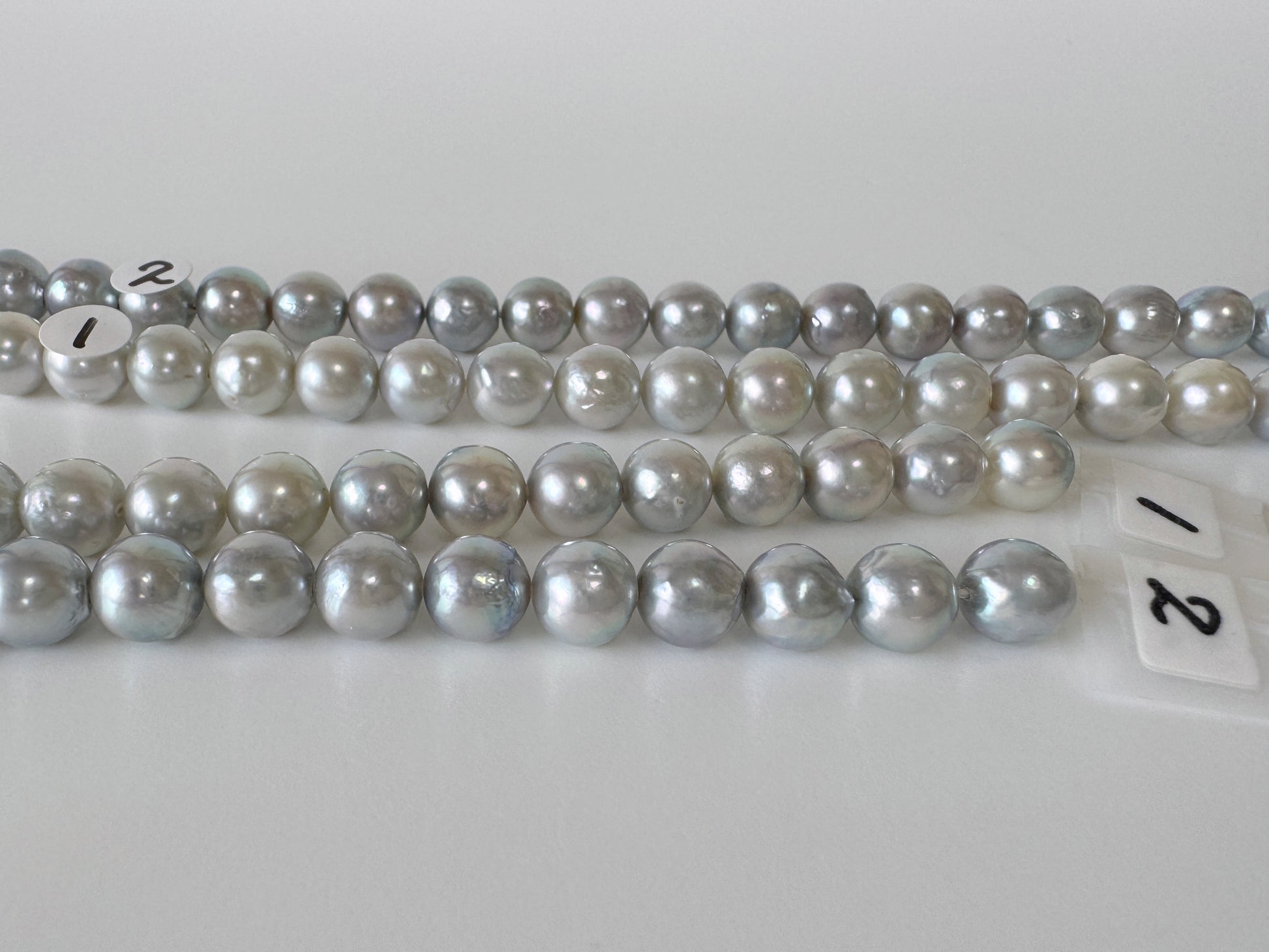 a collection of numerous silver and white pearls arranged in rows on a white surface.