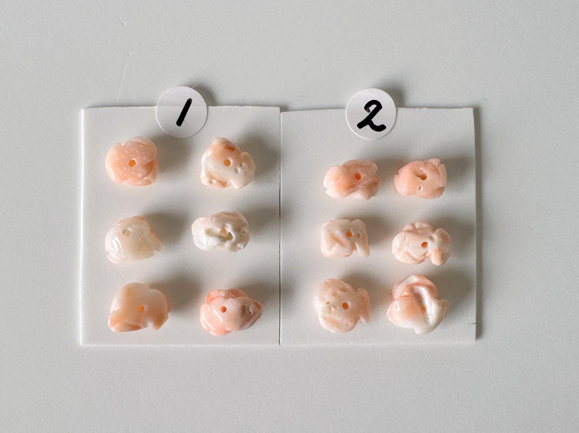 a collection of small, light pink objects arranged in two rows on a white background. Each row contains a total of nine objects, with the first row having four objects and the second row having five objects. The objects are positioned in a way that they appear to be in a grid-like pattern, with each row containing the same number of objects.