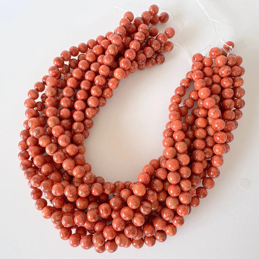 A collection of red beads arranged in a circular pattern, with the beads appearing to be made of a shiny material.