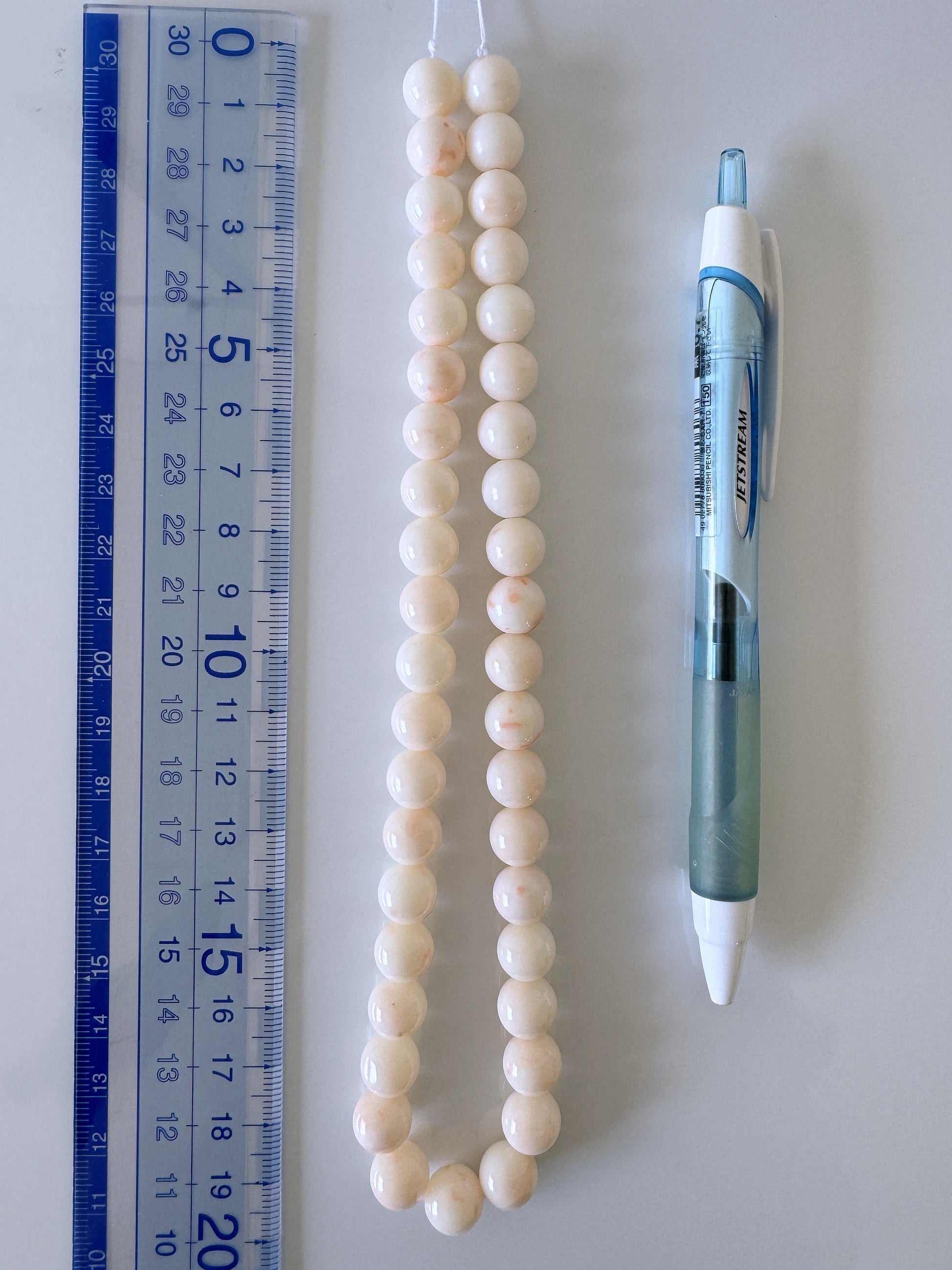 a white bead necklace next to a ruler