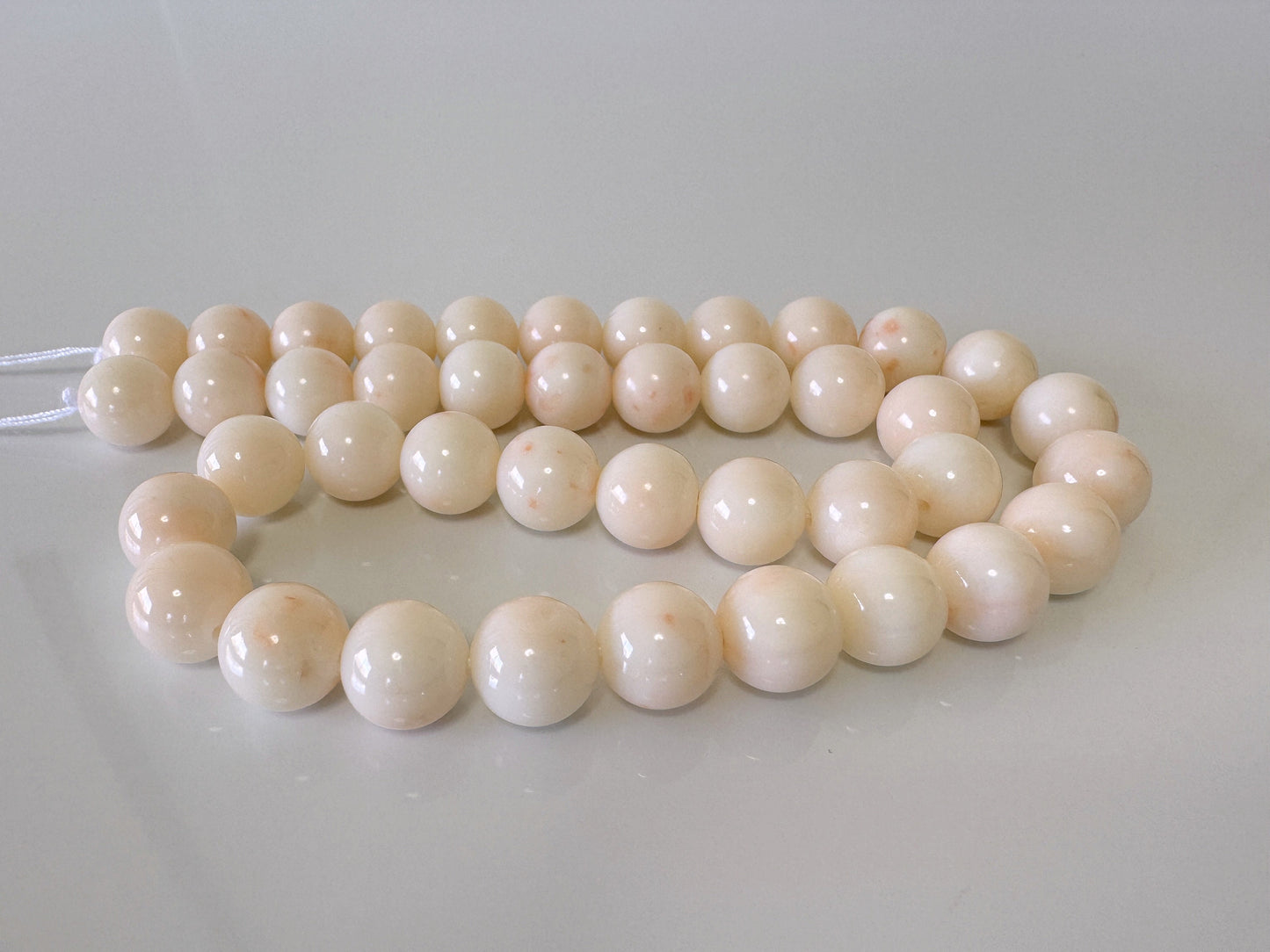 a string of white round beads on a white surface