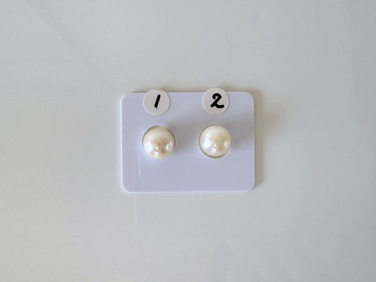 a pair of pearl earrings sitting on top of a white board