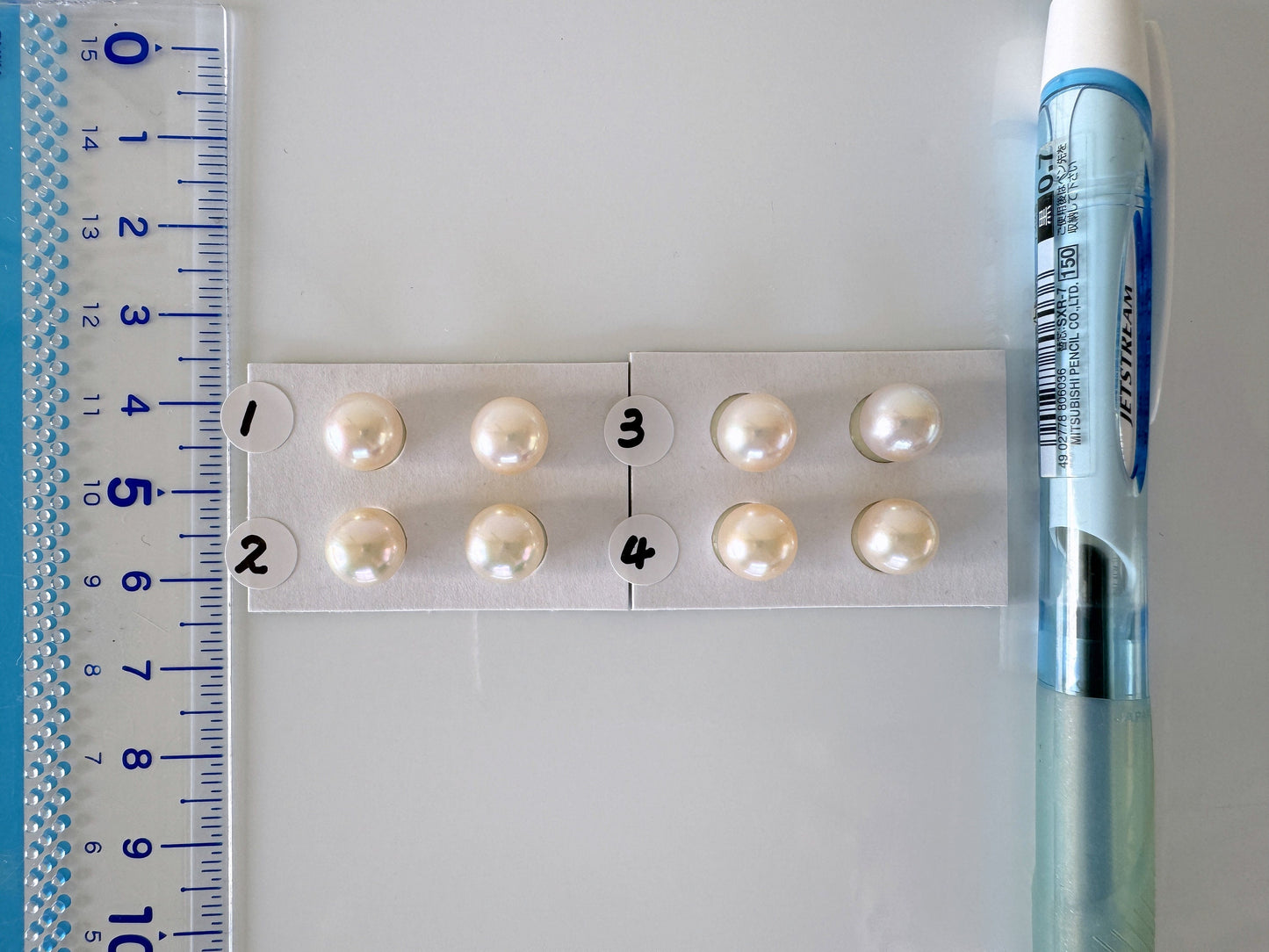 a ruler with pearls on it next to a pen