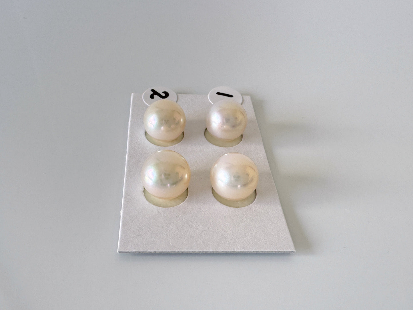 a set of three pearl studs on a white surface