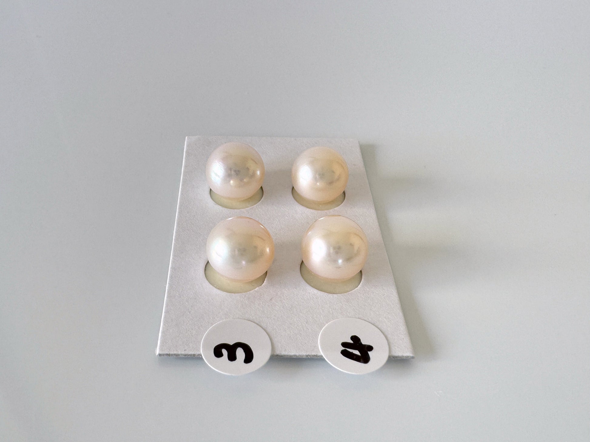 a set of four pearl studs sitting on top of a white surface