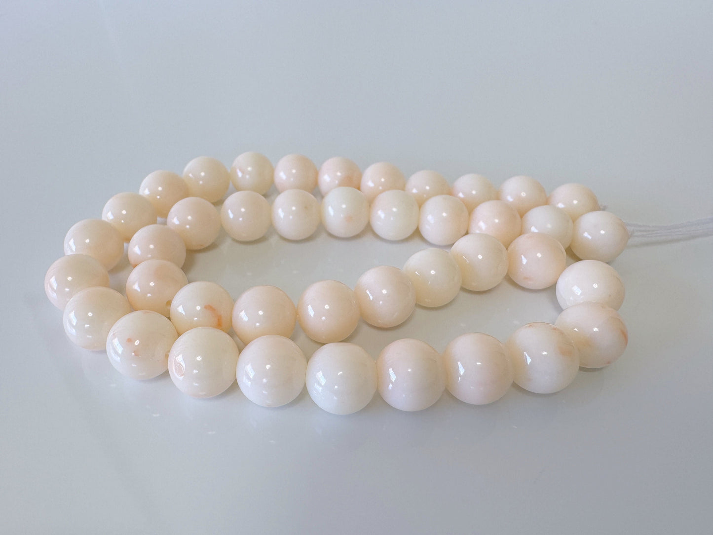 a white bead necklace on a white surface