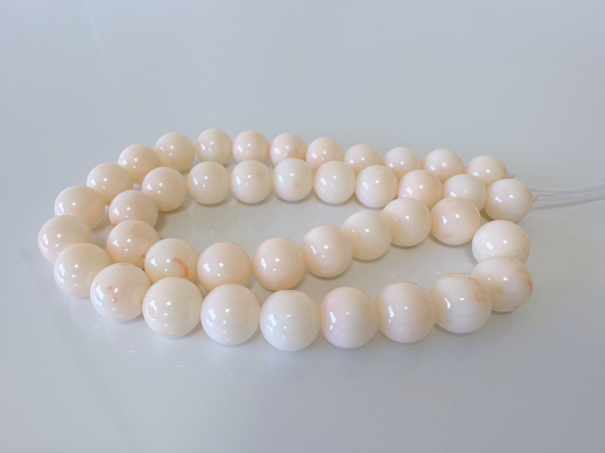 a white bead necklace on a white surface