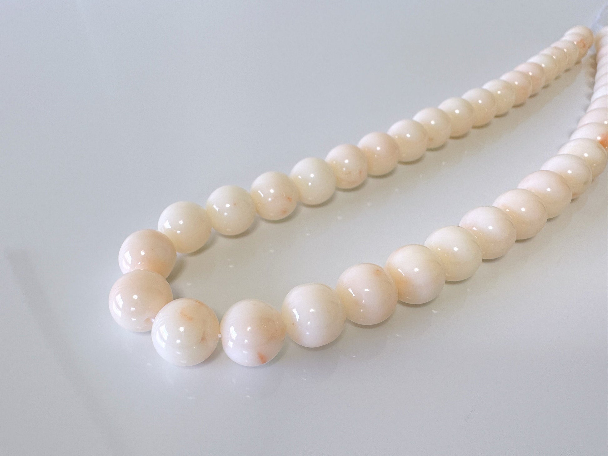 a white bead necklace on a white surface