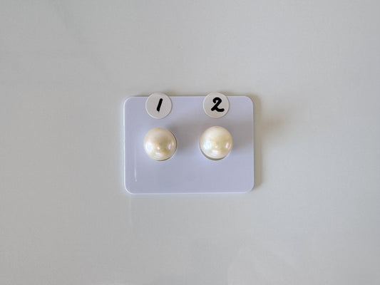 a pair of pearl earrings sitting on top of a white board