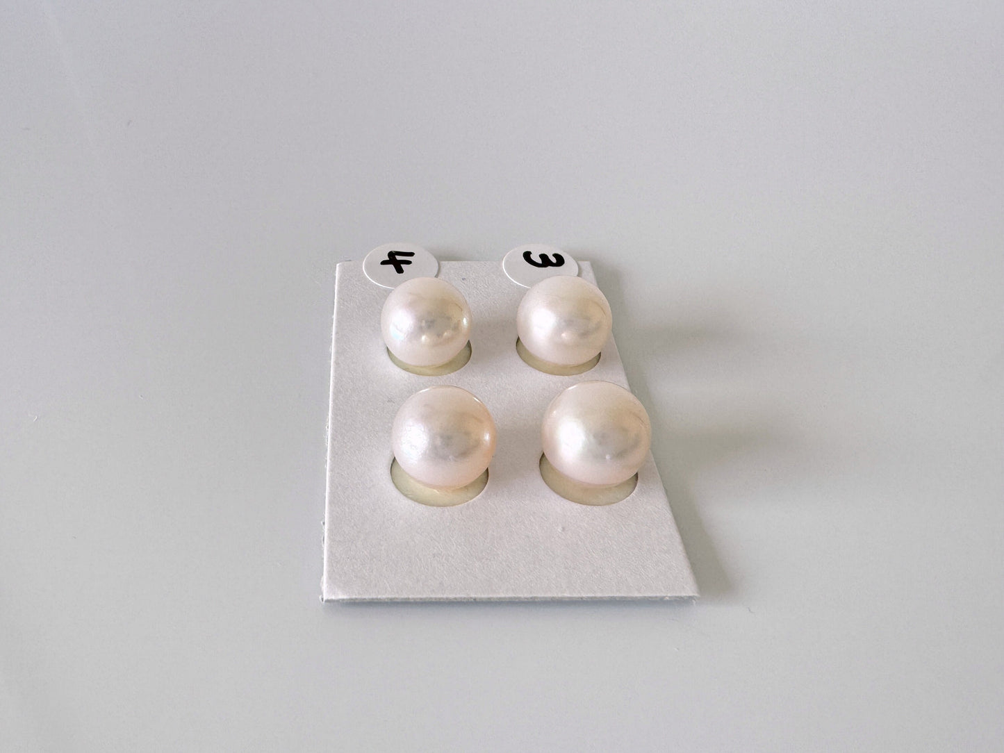 a pair of pearl earrings sitting on top of a piece of paper