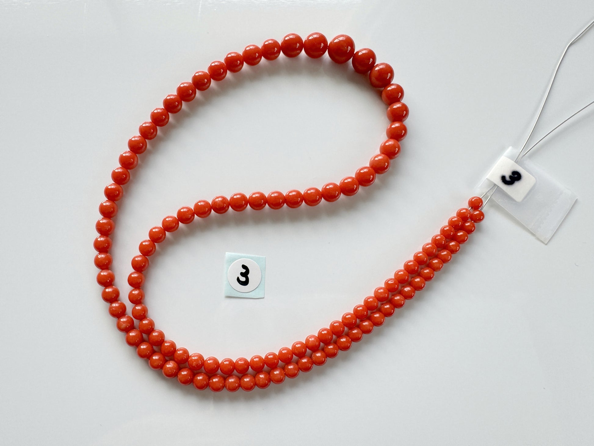 a red beaded necklace with a white tag on it