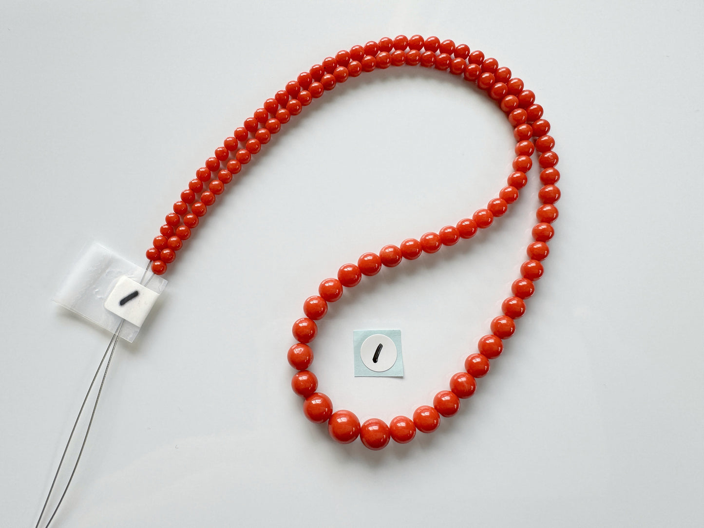 a red beaded necklace with a white square button