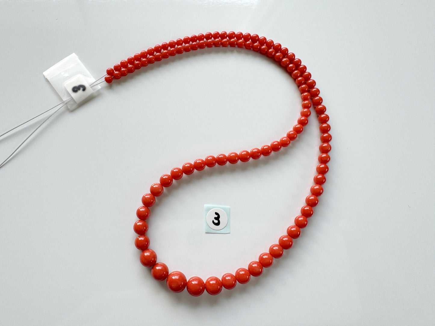 a red beaded necklace on a white surface