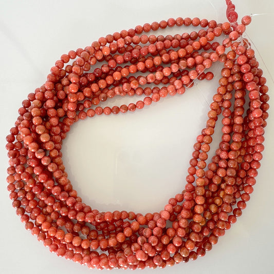 a strand of coral beads on a white surface