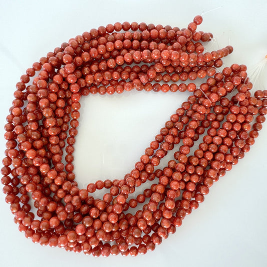 a strand of red coral beads on a white surface