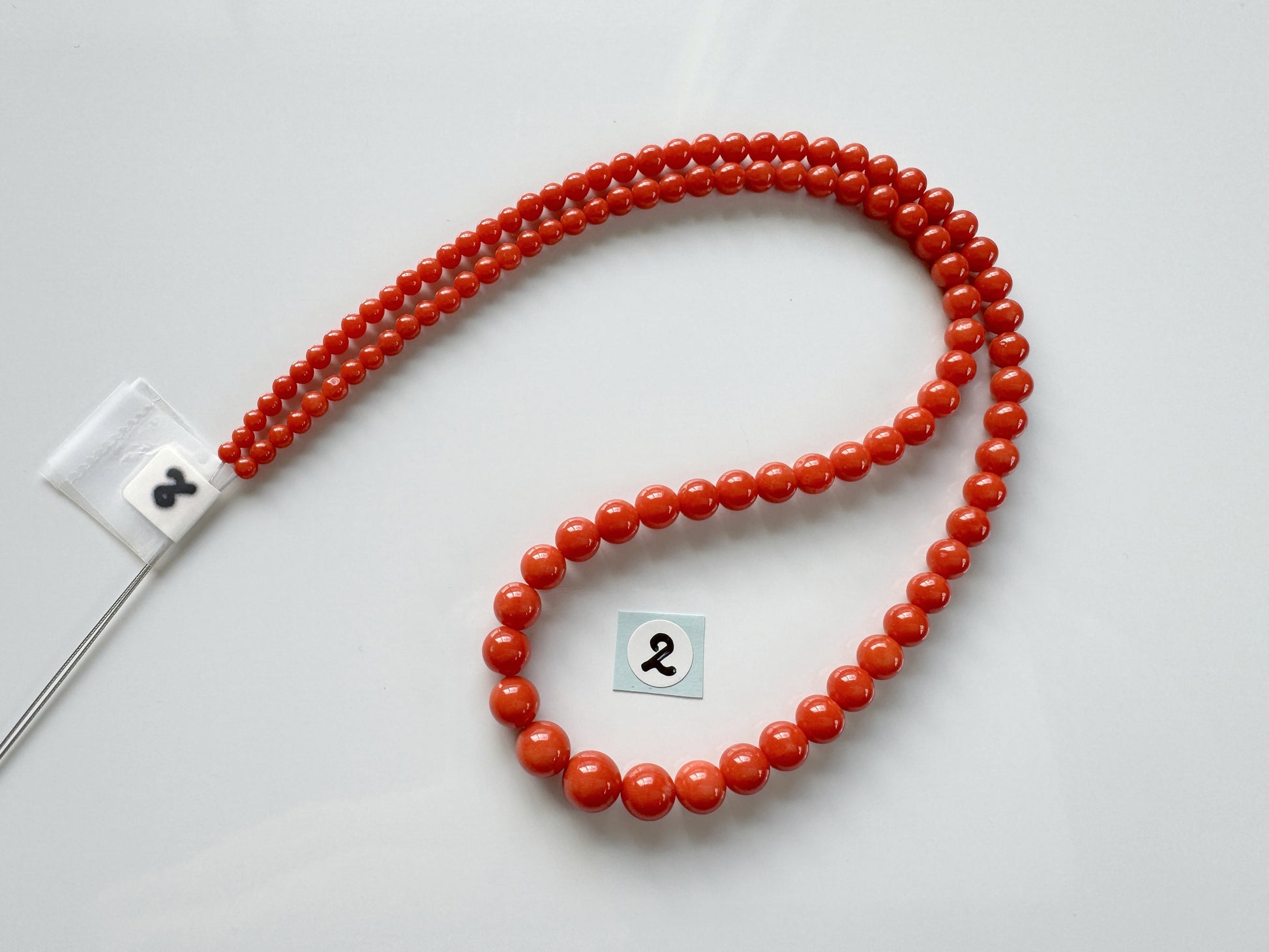 a red beaded necklace with a black and white number on it