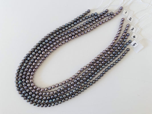 a long strand of black pearls on a white surface